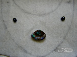 deciding what goes where   the tiny black stones are star diopside, center piece is the opal